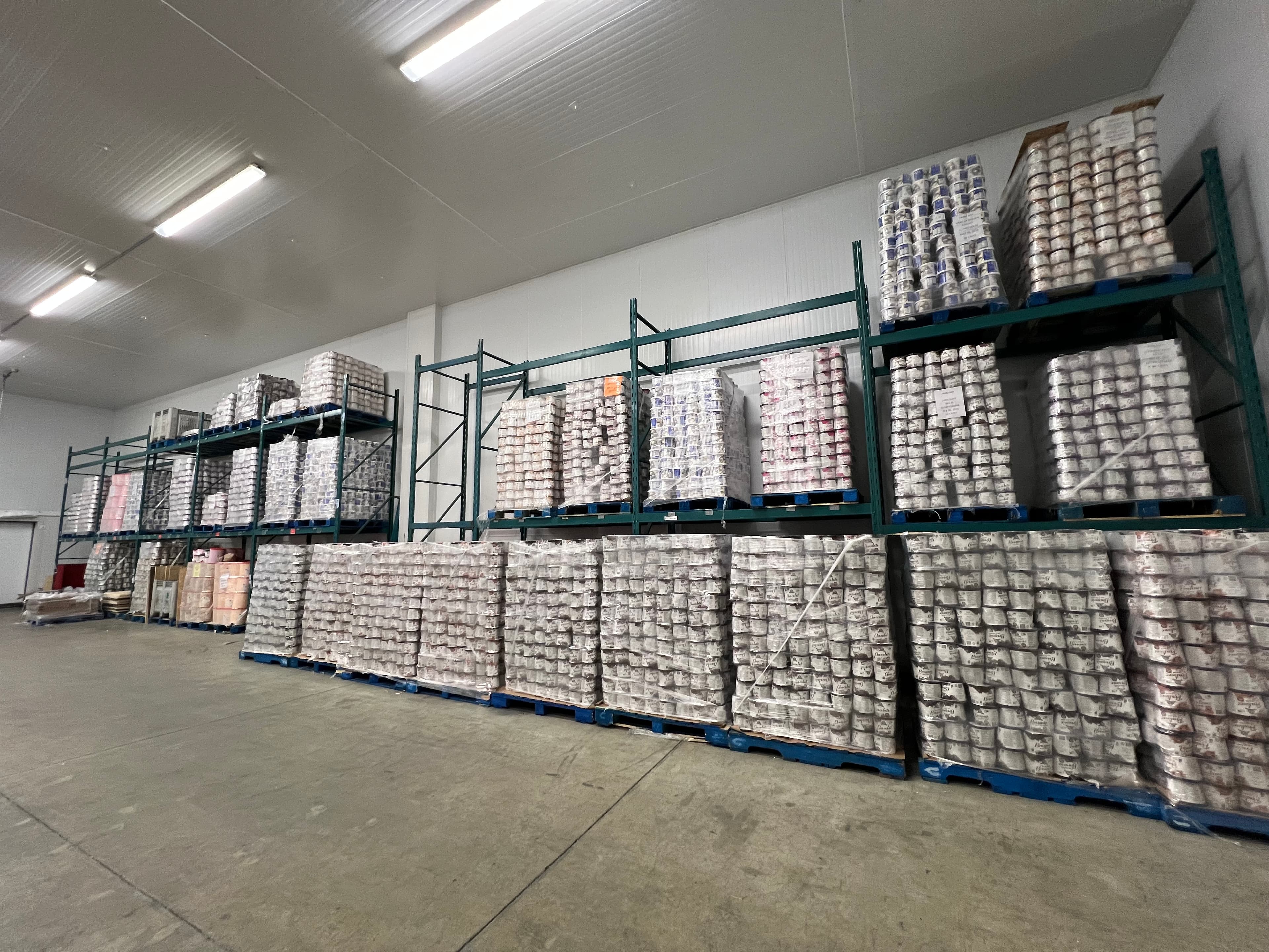 Pallets of packaged ice cream stacked on racking down both sides of the freezer aisle.